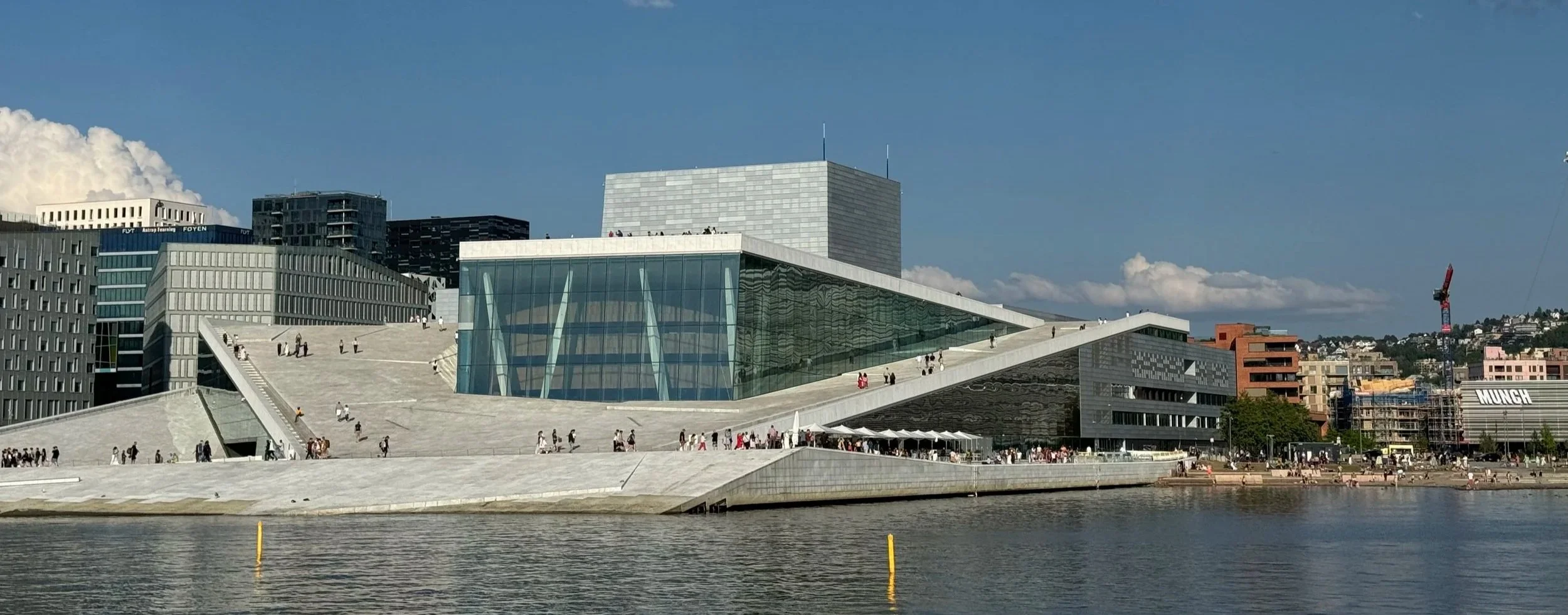 Oslo Opera House exterior viewed across the harbor, modern white marble architecture reflecting on the water in Oslo, Norway