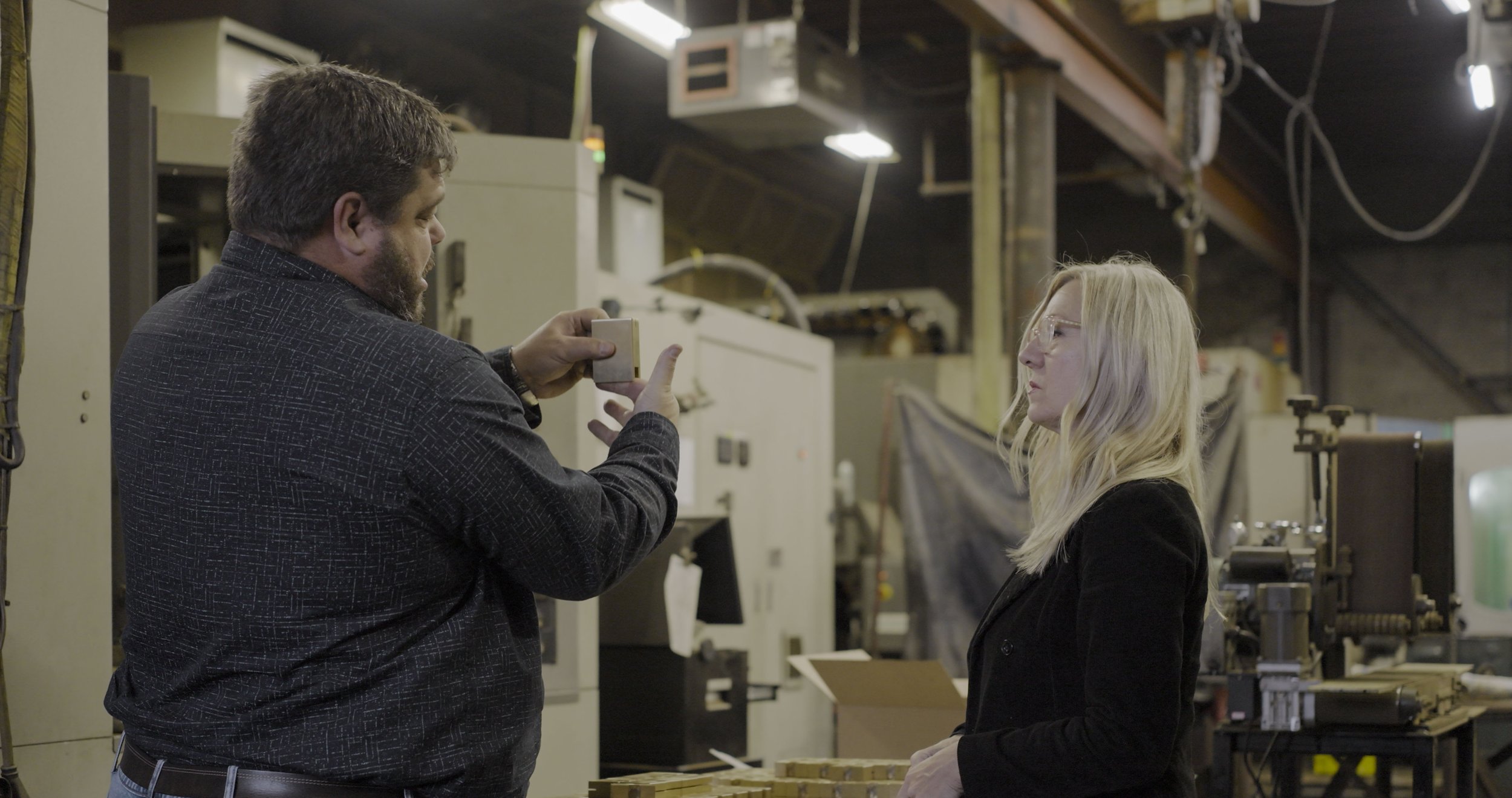 Markwart Metals specialist reviewing precision metal components with a client inside an industrial manufacturing facility