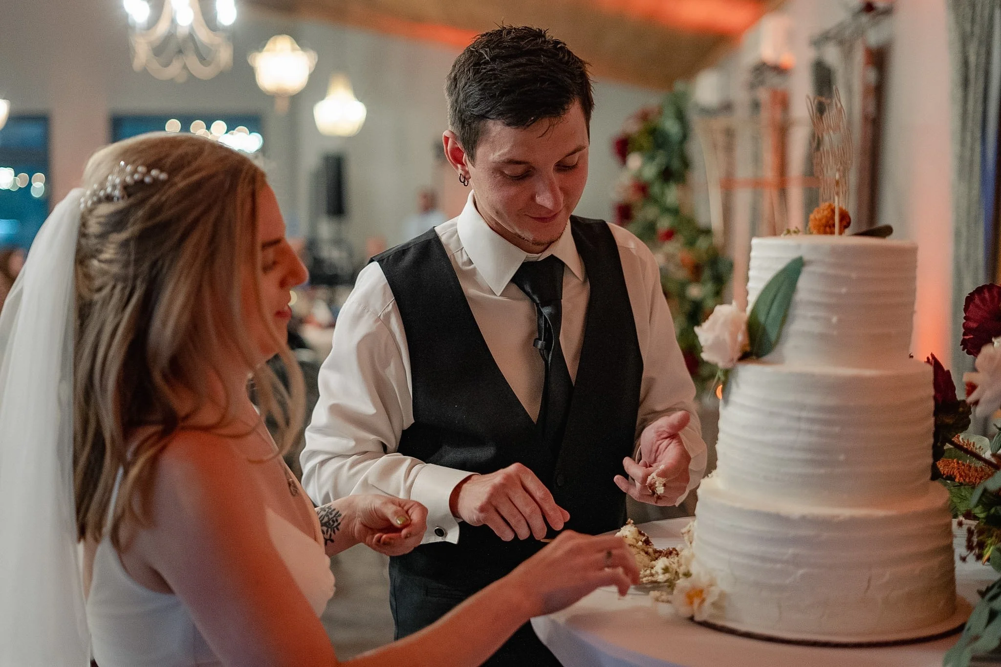 A bride and groom cutting a wedding cake together at their reception.