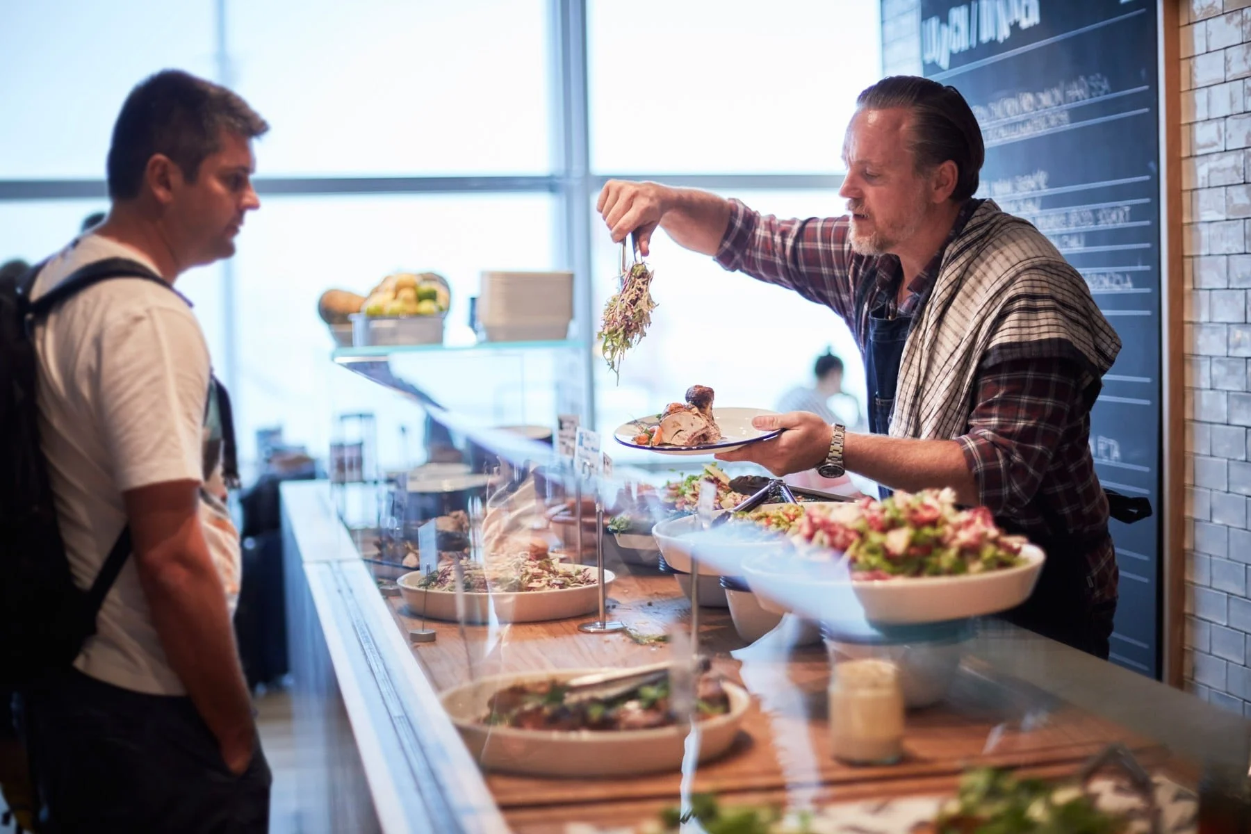A man serving food to a customer at a restaurant counter.