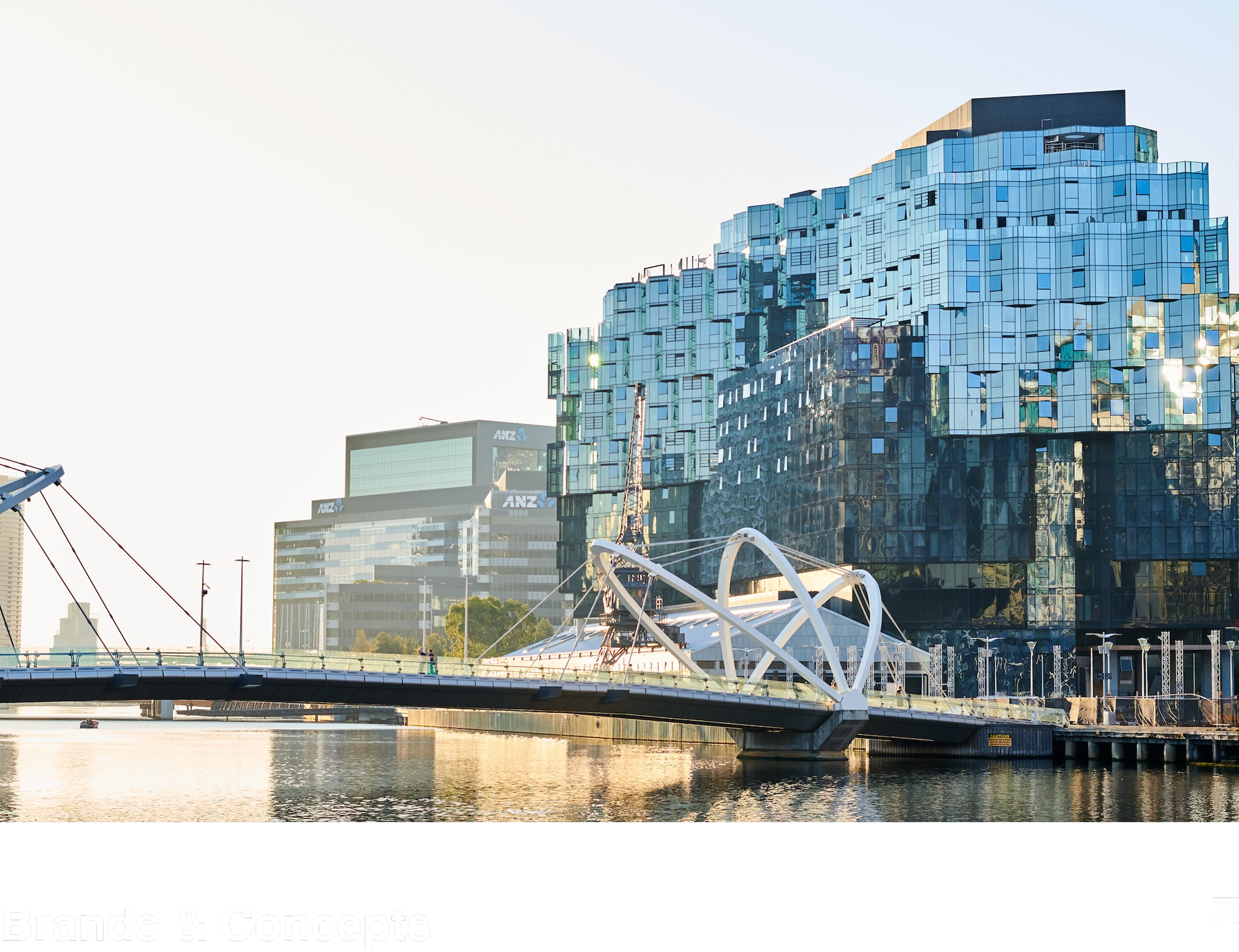Cityscape featuring modern glass buildings, a bridge over a river, and a clear sky.