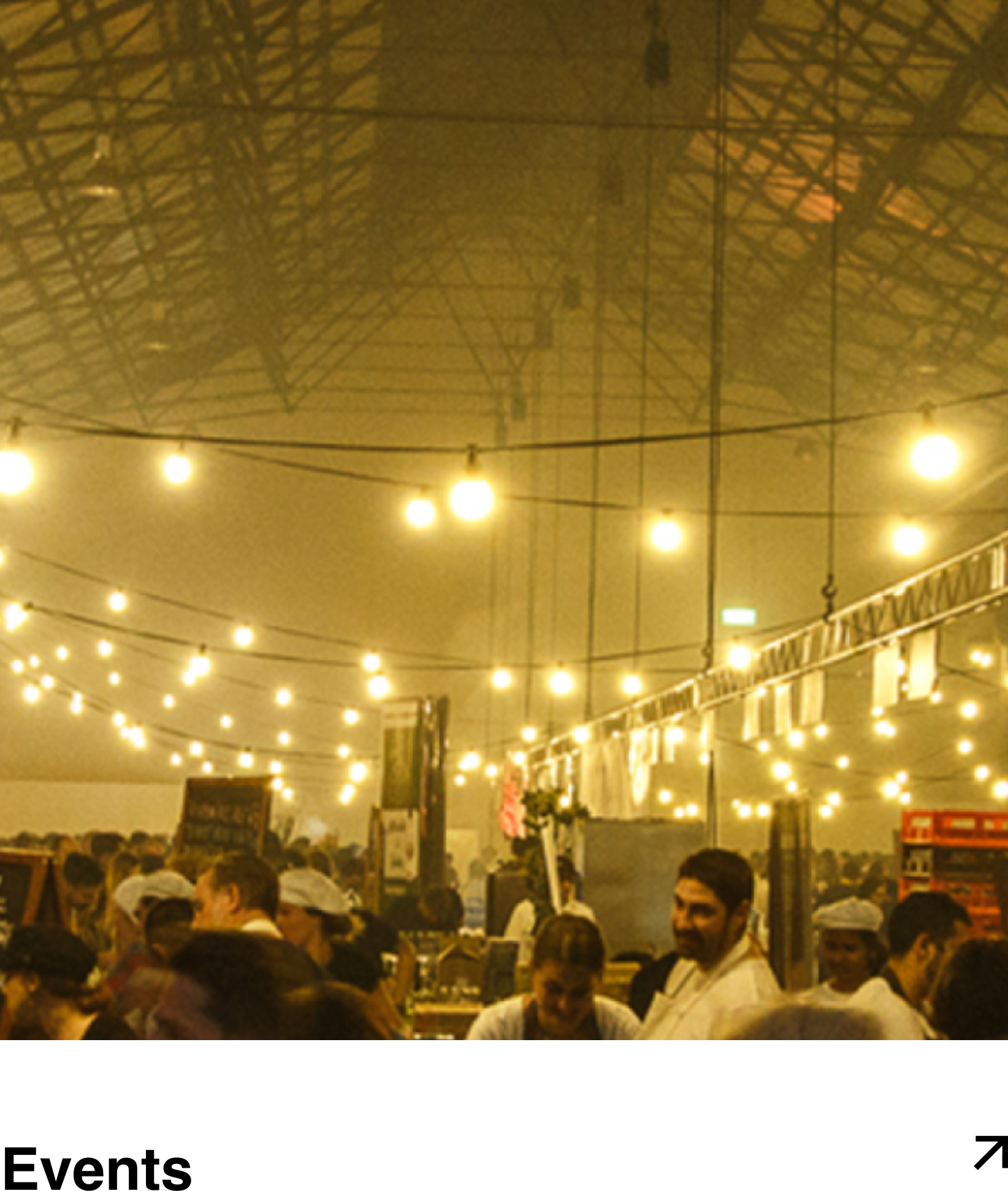 People gathered at an indoor event with string lights hanging from the ceiling, creating a warm ambiance.
