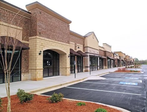 Empty retail storefronts in a shopping center with parking lot and marked handicapped spaces.