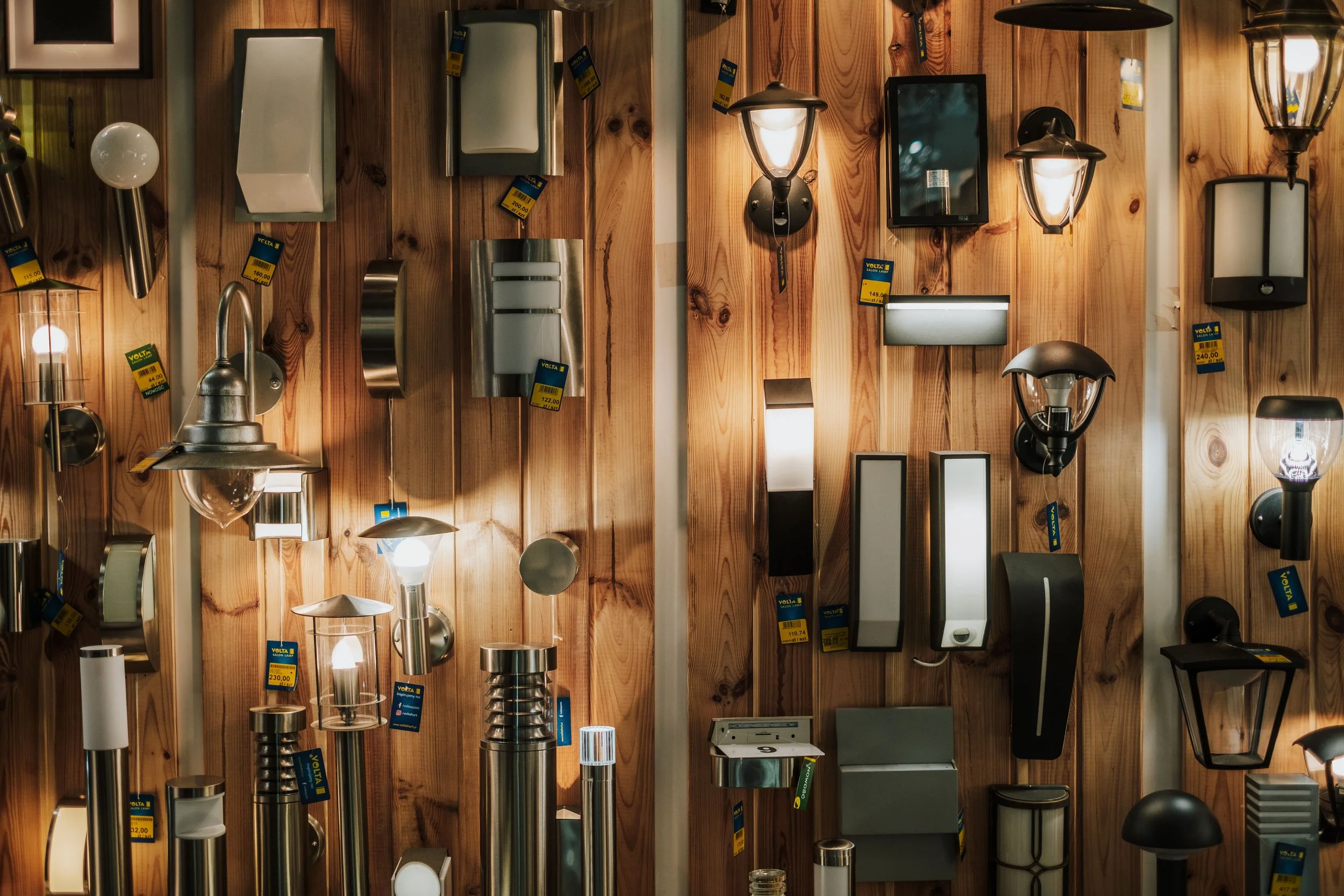 A wooden gallery wall showcasing a variety of styles of light-fixtures