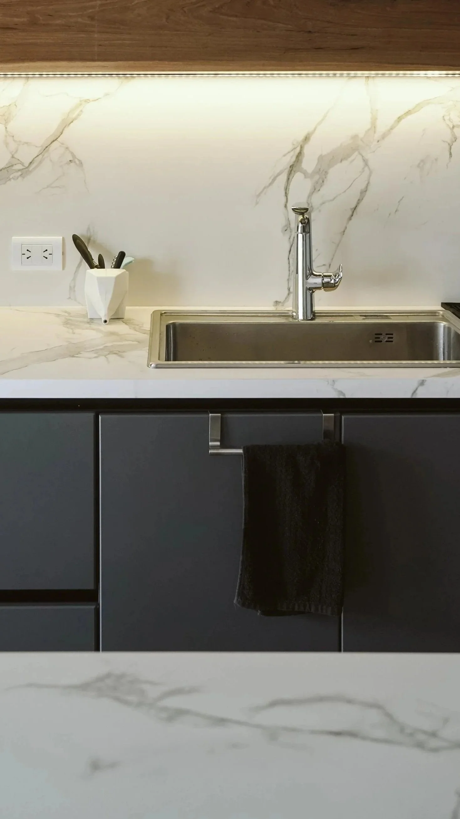 photo of a kitchen island, counter and backsplash all done in a quartz or porcelain designed to mimic the look of white marble.