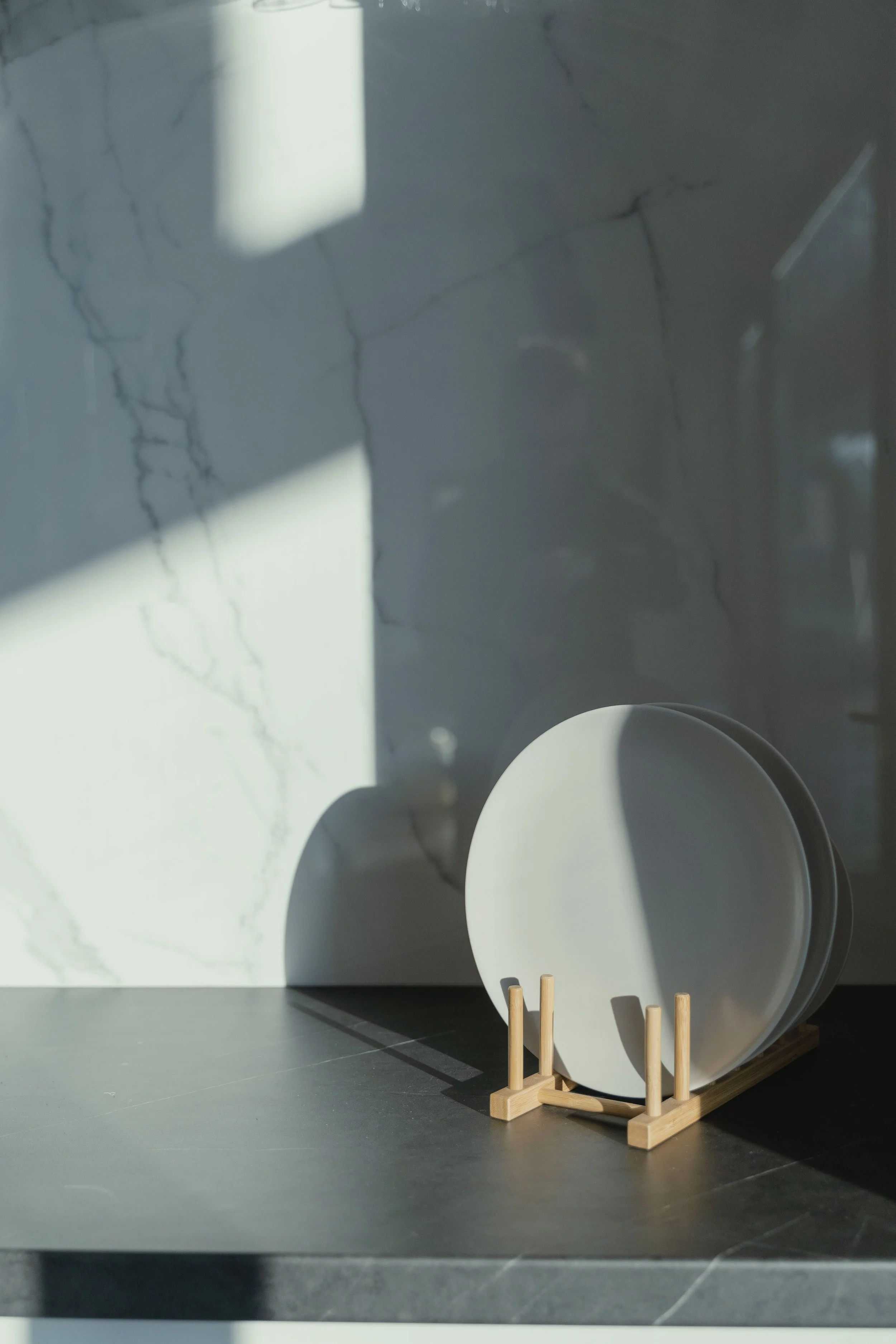 a kitchen counter with a marble-like backsplash and a plate sitting on the counter in a bamboo stand.
