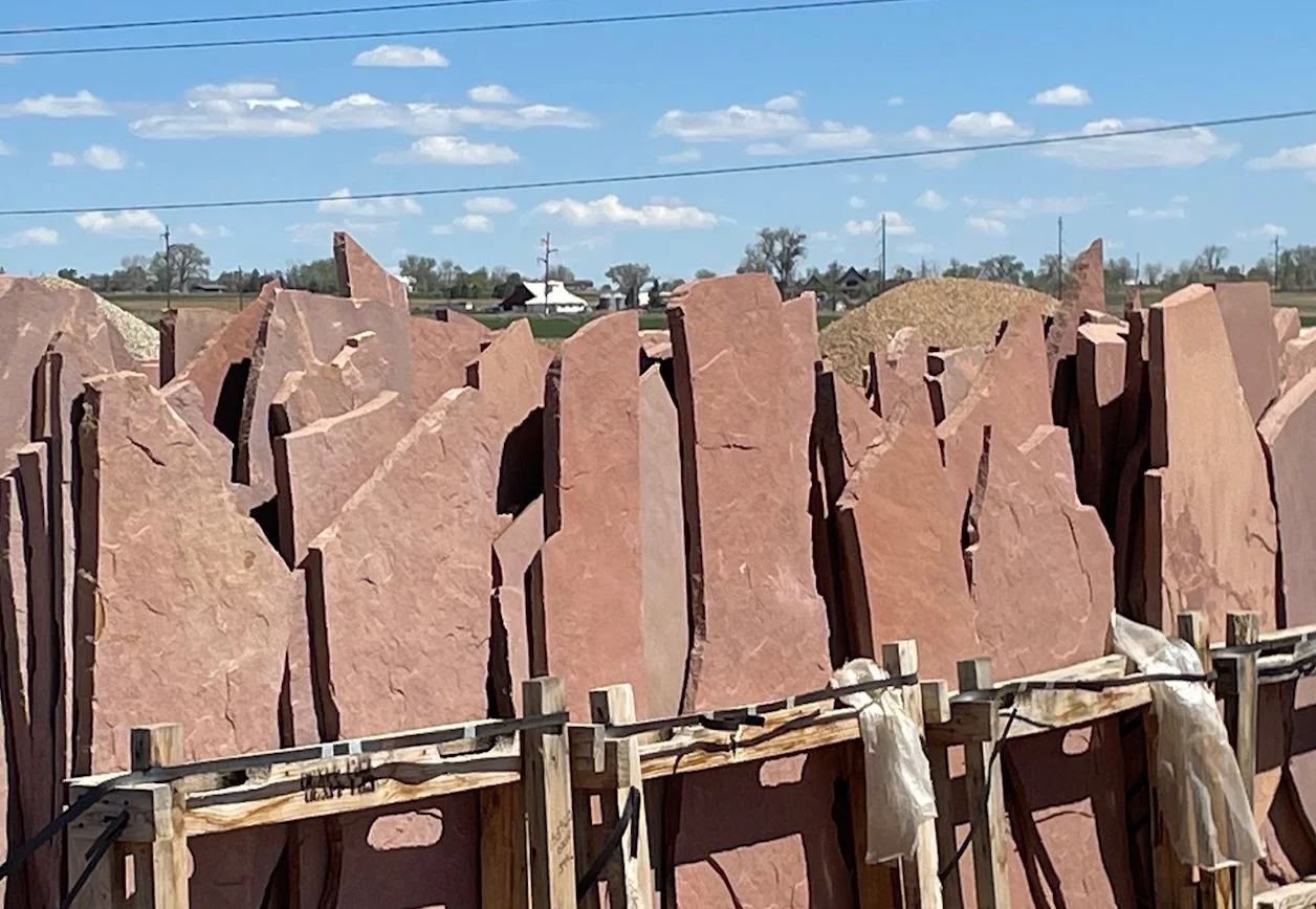 photo taken by Lori Symmes of red granite slabs standing upright in a rack display outside in Colorado