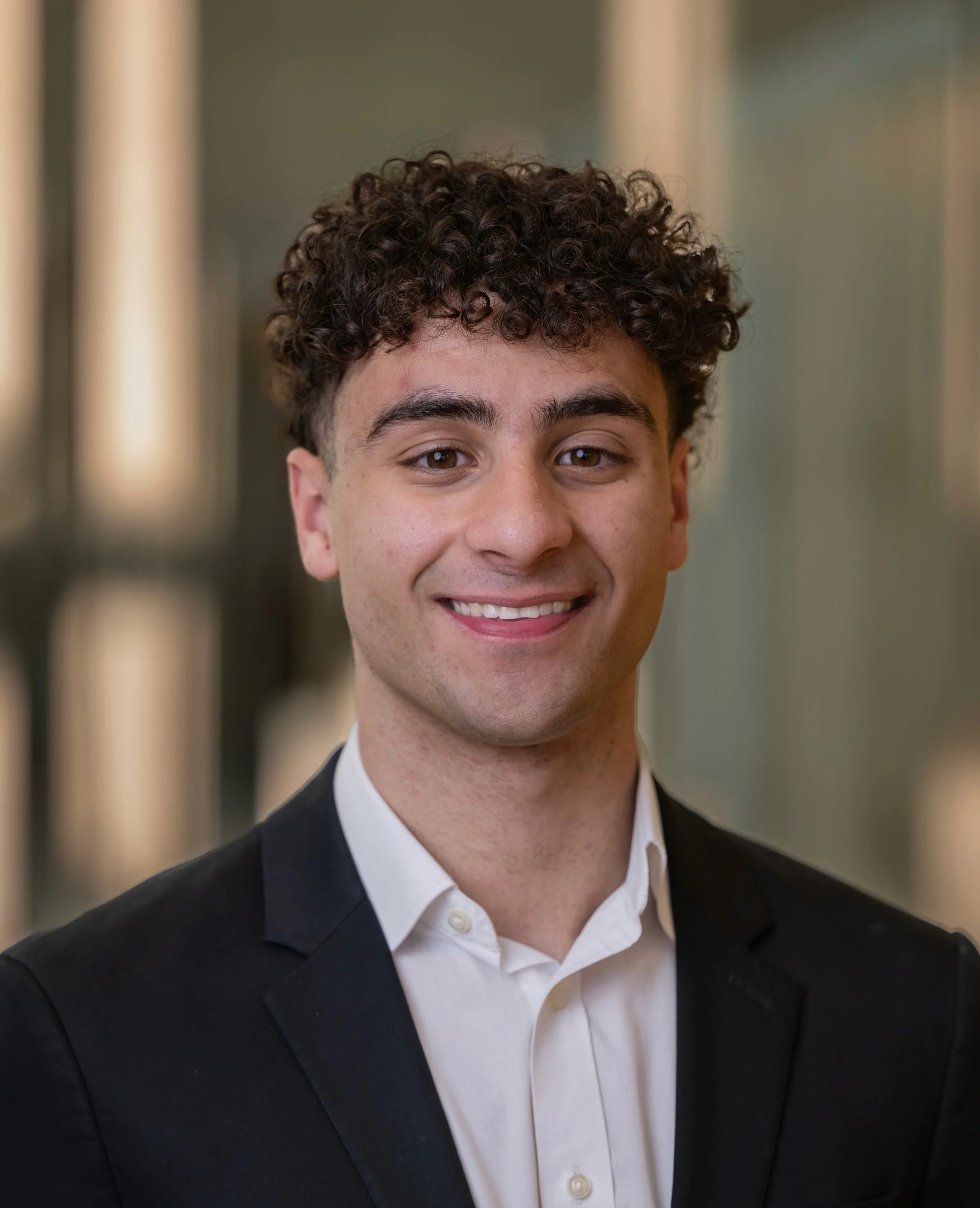 Professional young man with curly hair smiling in an indoor office setting