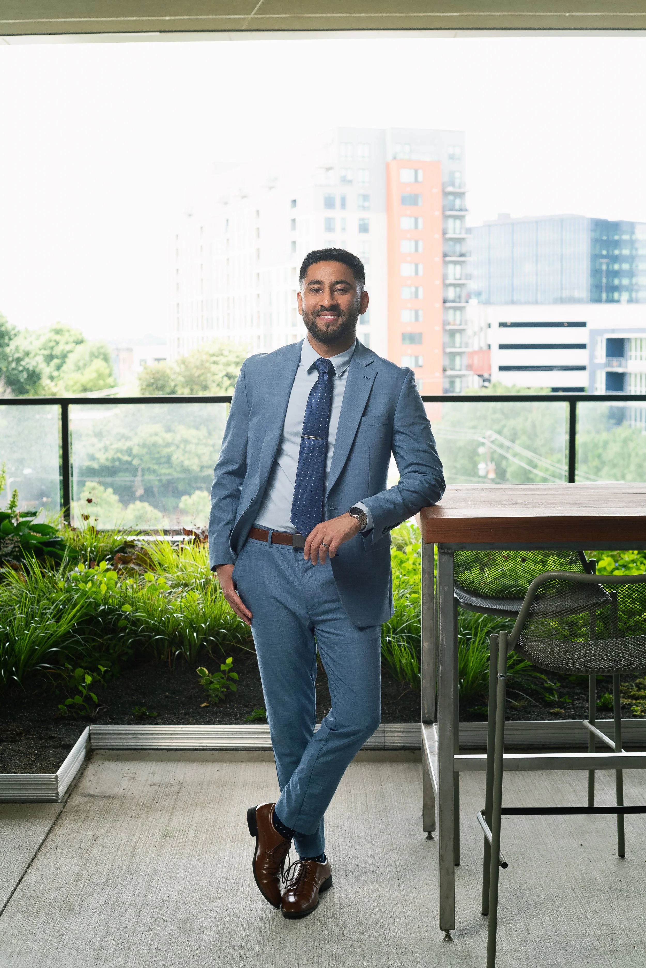 Professional photo of Dr. Anoop Takher smiling against a green open air patio background.