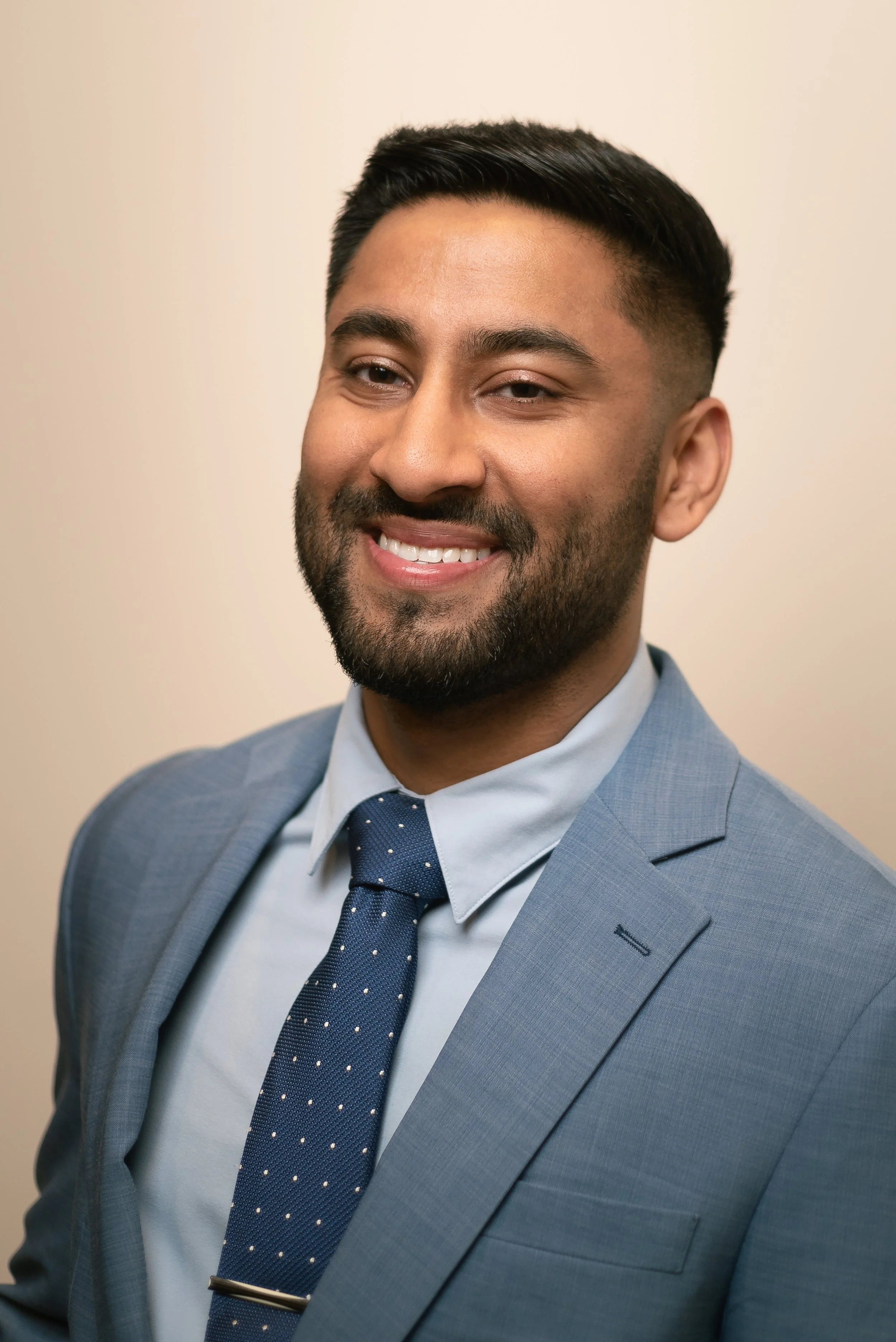 Professional headshot of Dr. Anoop Takher smiling against a neutral background.