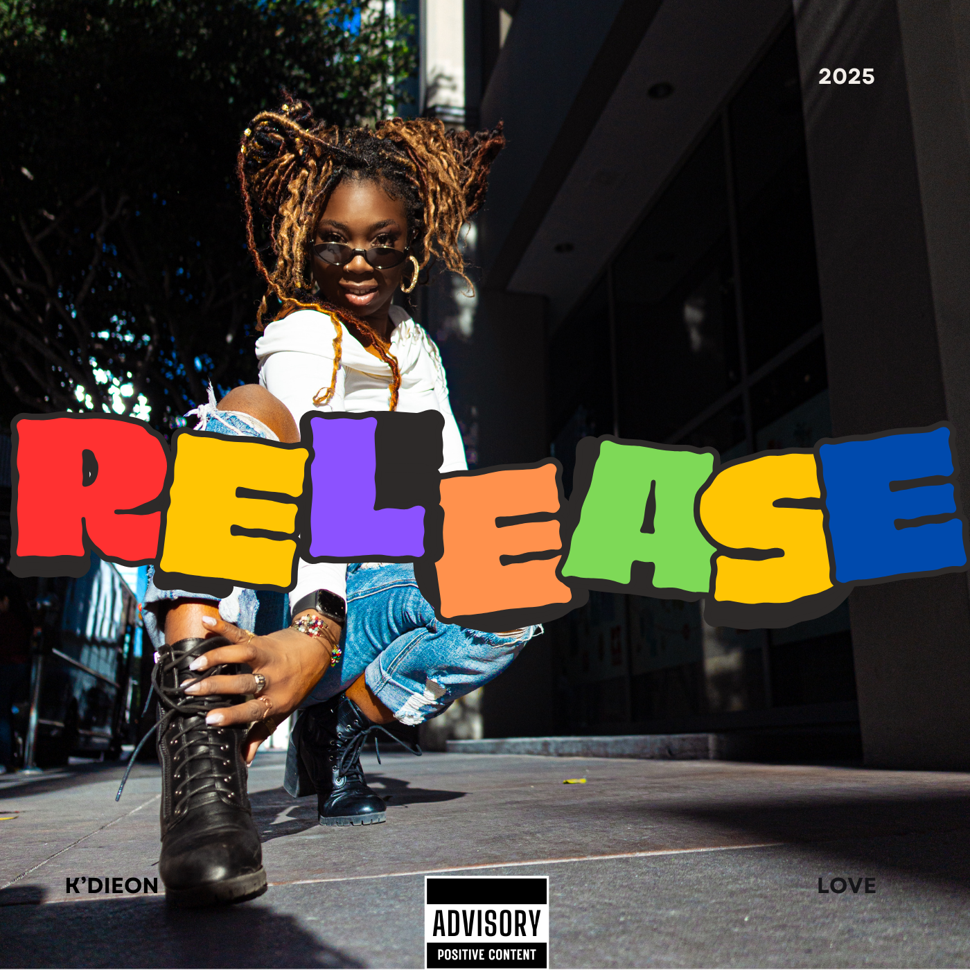 A woman with dreadlocks, sunglasses, and jewelry, squatting outdoors near a modern building with dark windows, holding a colorful sign that says 'RELEASE' in bold, multicolored letters. The image has text indicating the year 2025 and words 'K'DIEON' and 'LOVE', with a parental advisory label at the bottom.