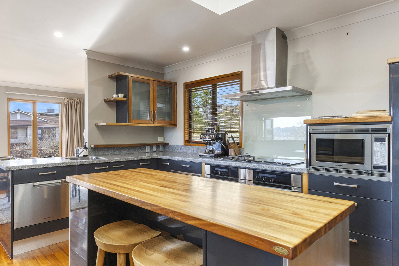 Modern kitchen with wooden accents, blue cabinets, stainless steel appliances, and a wooden island counter