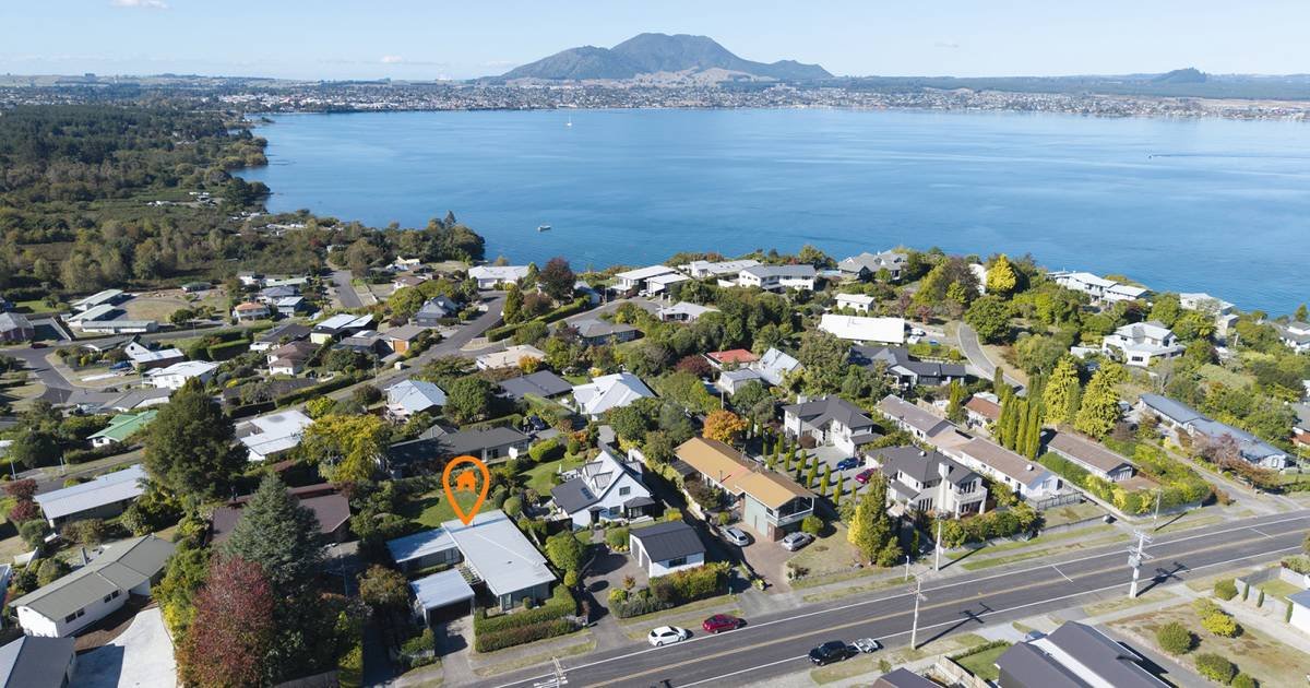 Aerial view of a residential neighborhood by a large body of water with mountains in the background.
