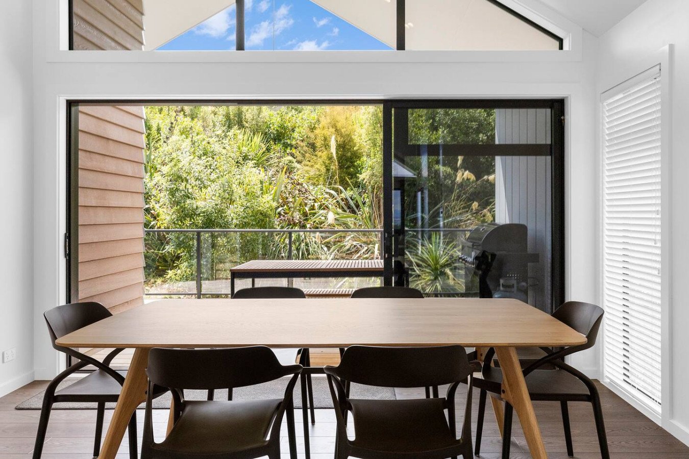 Modern dining room with large glass sliding door leading to a lush outdoor garden