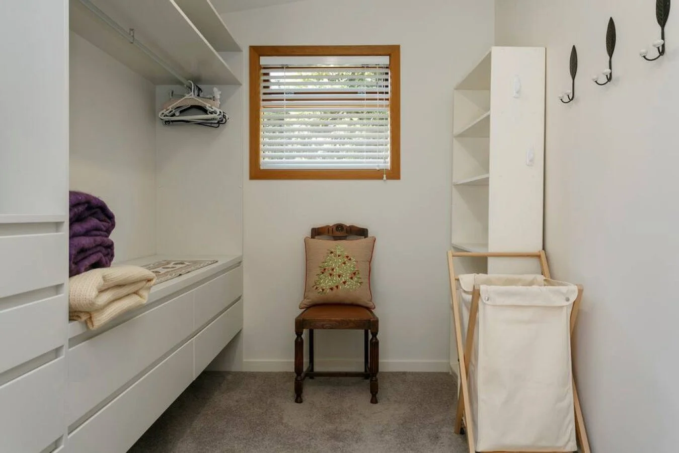 Small, organized laundry room with a window, shelf, folding area, and laundry basket.