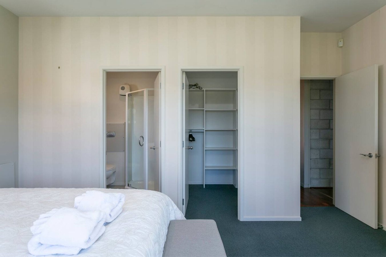 Bedroom with bed, folded towels on the bed, and closet space with shelves