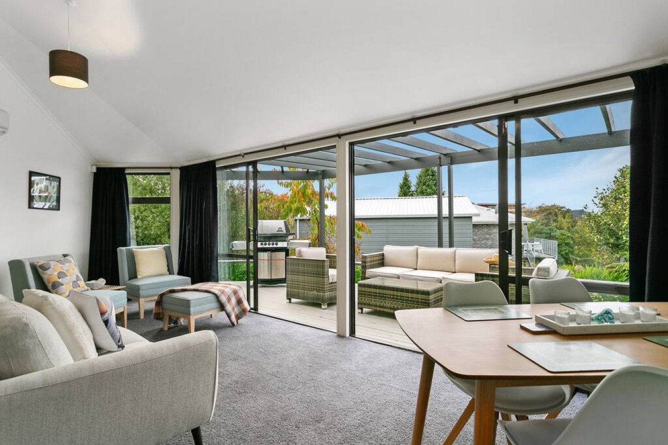 Living room with sliding glass doors leading to a patio, outdoor seating, and a grill.