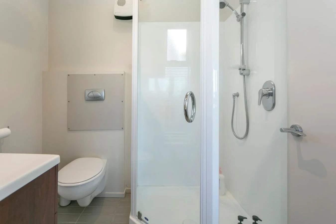 Bathroom with a toilet, shower enclosure, and white walls.