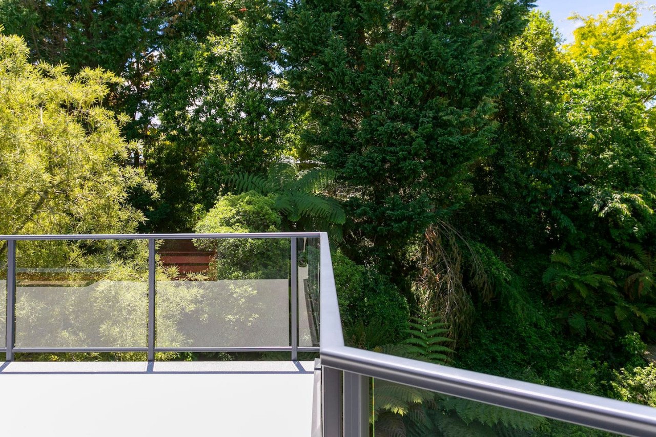 Balcony with metal railing overlooking dense green trees and foliage.