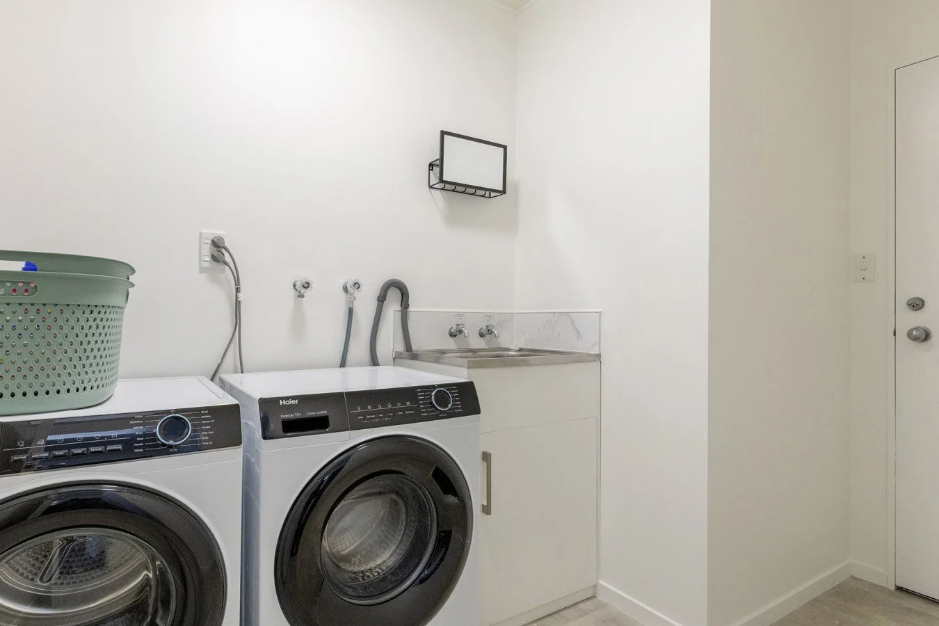 Laundry room with washing machine, dryer, laundry sink, and a small wall-mounted mirror.