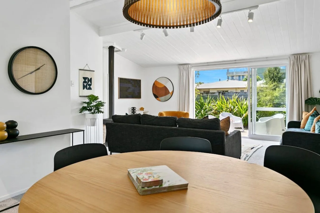 Living room with large window, black sofas, and outdoor garden view.