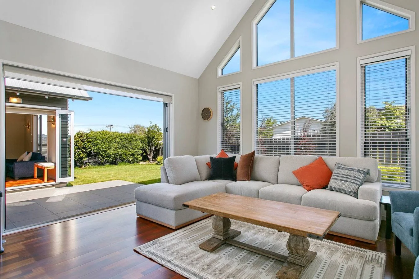 Living room with large windows and sliding glass door showing a backyard with green grass and bushes.