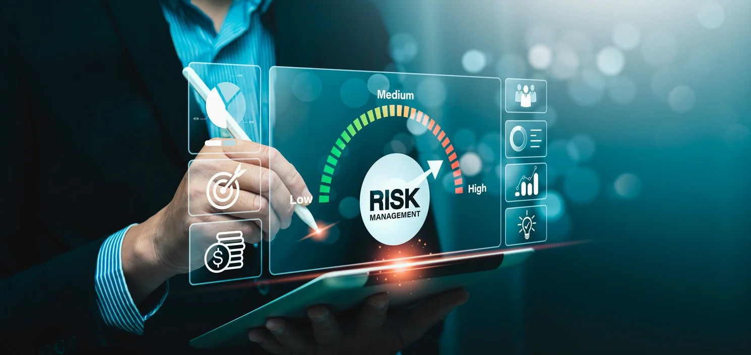 Person in a suit holding a tablet with a digital interface showing risk management graphics, including a risk gauge from low to high, a target icon, a dollar sign, and various data charts and icons.