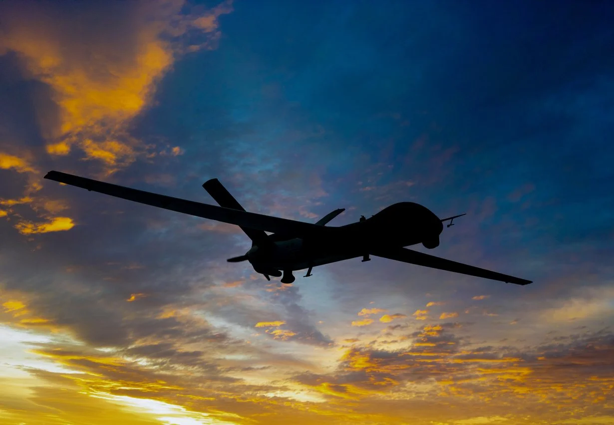 Silhouette of a small airplane flying in a colorful sunset sky with orange and blue clouds.