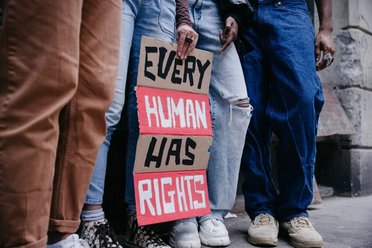 People standing in a protest holding a sign that reads 'Every Human Has Rights'