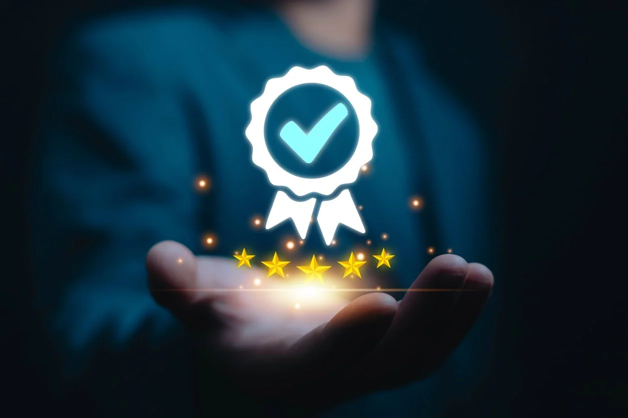 A person's hand holding a glowing holographic icon of a checkmark badge, with a five-star rating below, in a dark background.