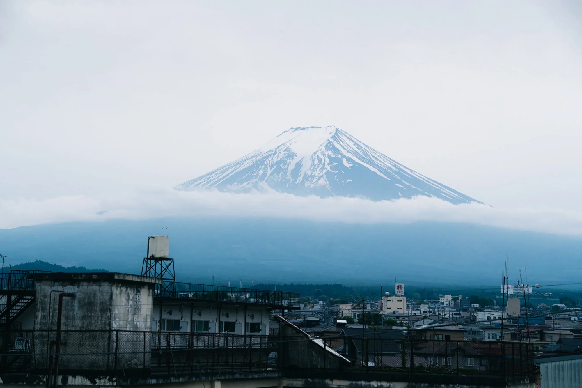 東京の都市景観と背景にそびえる富士山。雲が山の下に広がっています。