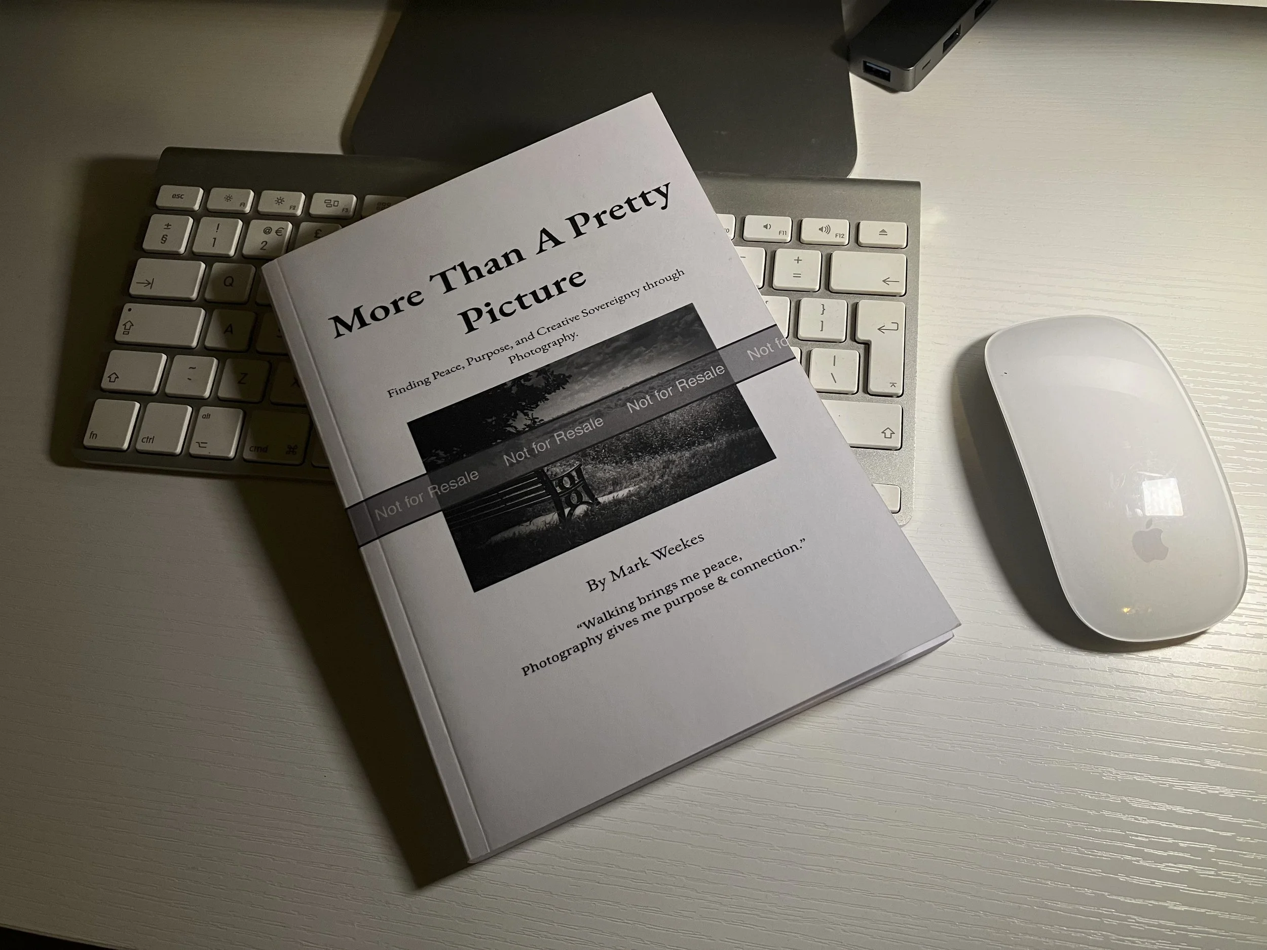 Proof copy of More Than a Pretty Picture by Mark Weekes, front cover, on desk alongside Apple keyboard and mouse