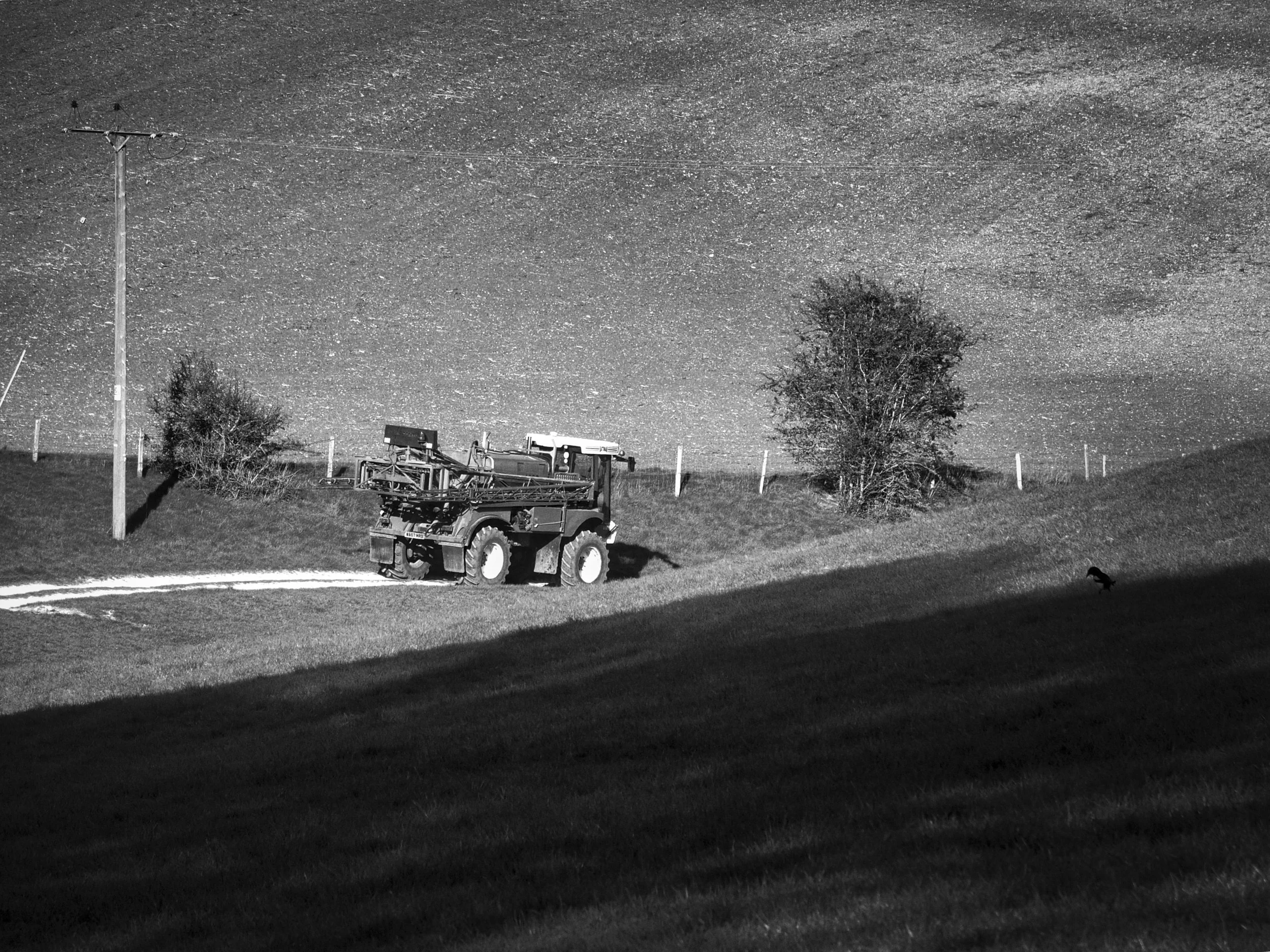 Farm machinery working the fields on a sunny spring morning in the Chiltern Hills, photographed in black and white by Mark Weekes