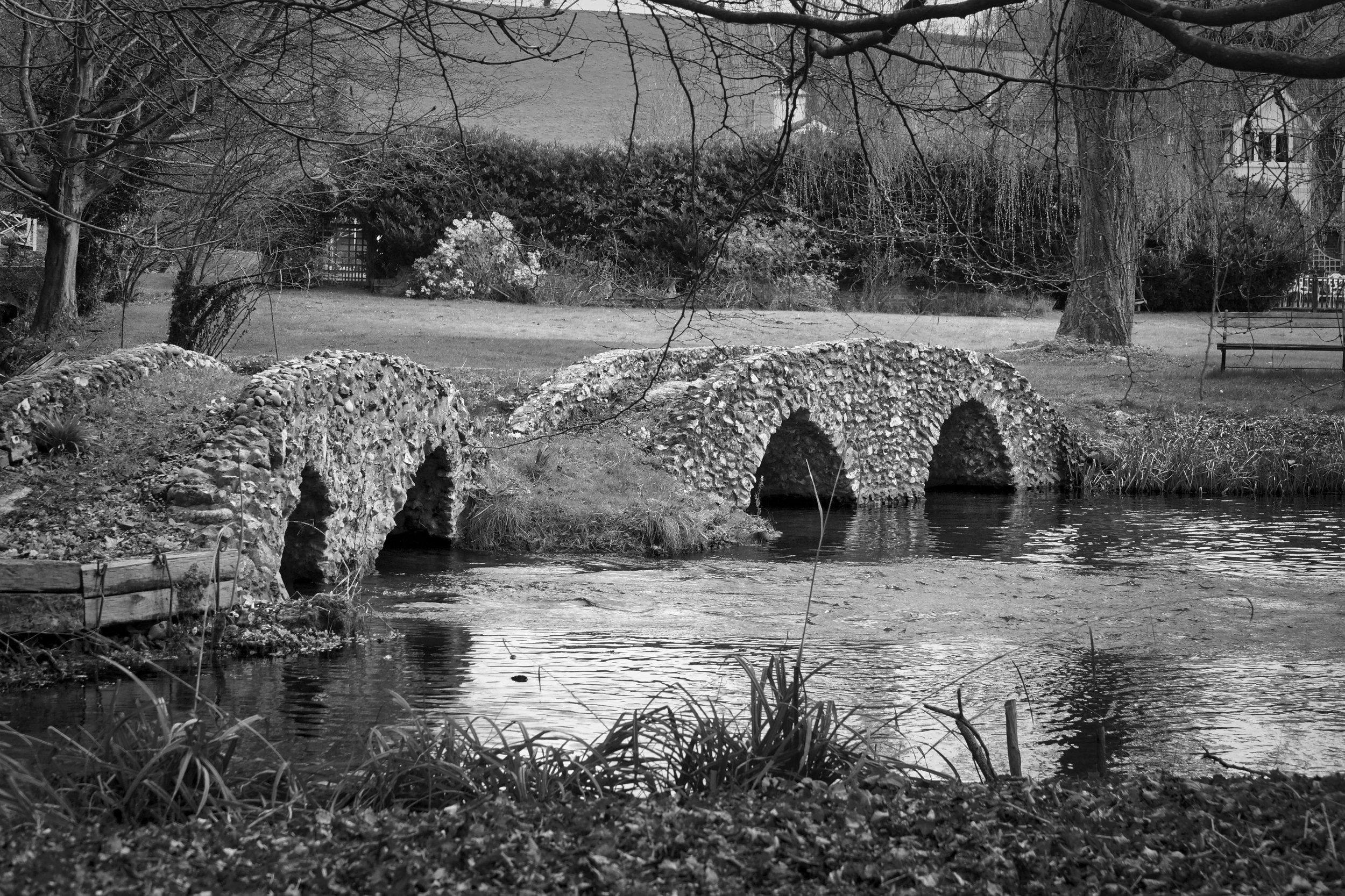 Flint-faced arched bridges over the River Chess at Mill Farm, Latimer, Chess Valley, Buckinghamshire, black and white