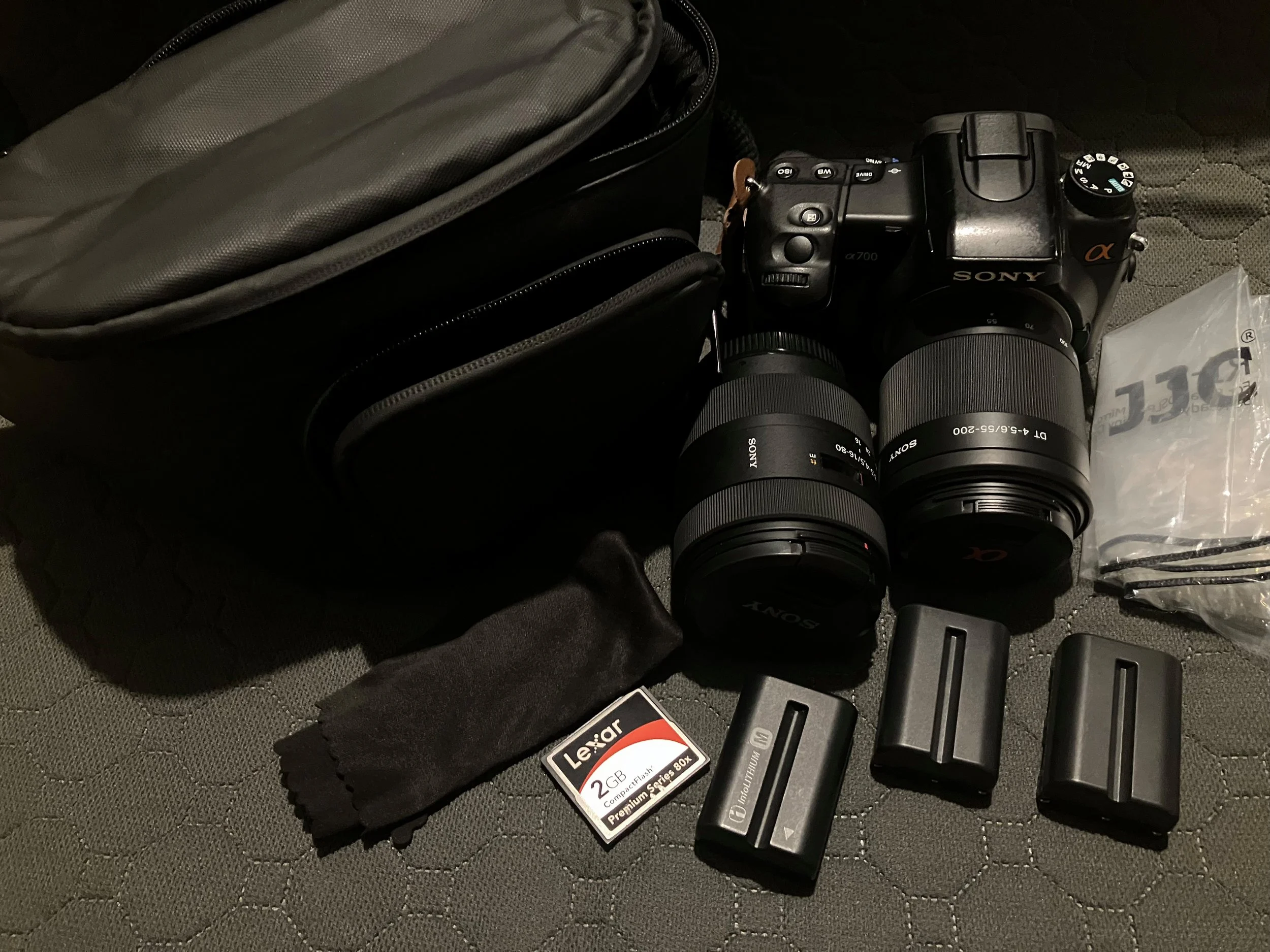Sony Alpha A700 camera with Zeiss 16-80mm and Sony 55-200mm lenses, three batteries, CF card and lens cloth laid out alongside a hip pack — the complete walking photography kit