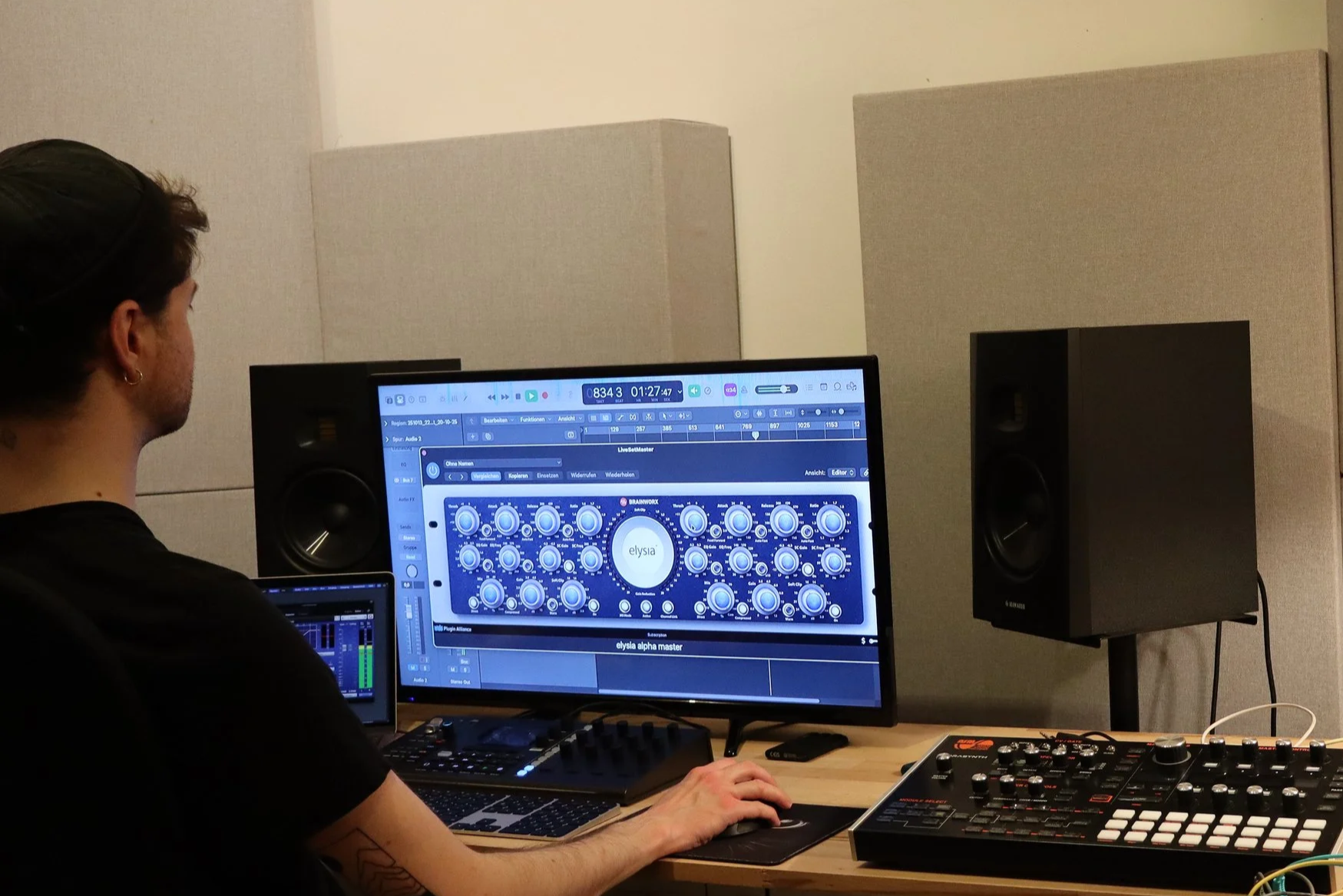 Person working on music production with computer and audio equipment in a studio.