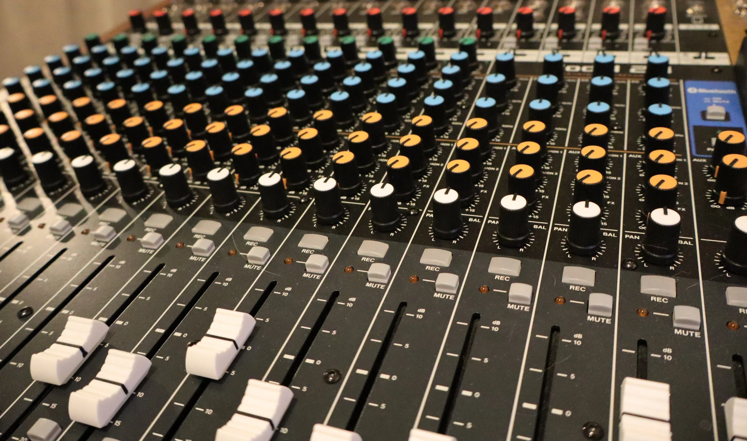 A professional audio mixing console with multiple knobs, sliders, and buttons used for sound control and mixing.