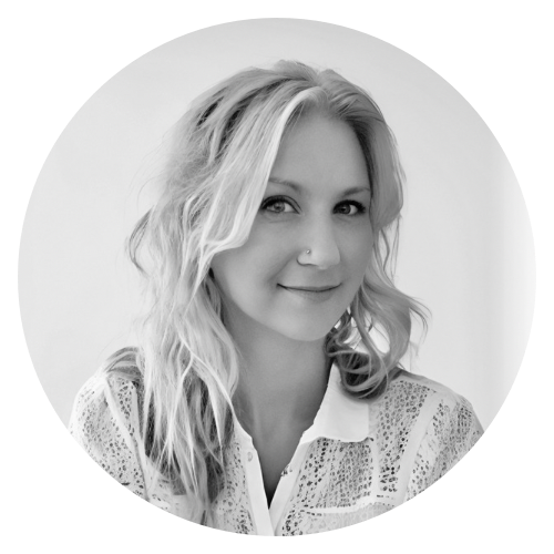 Black and white portrait of a young woman with wavy blonde hair, smiling slightly, wearing a patterned blouse with a collar.