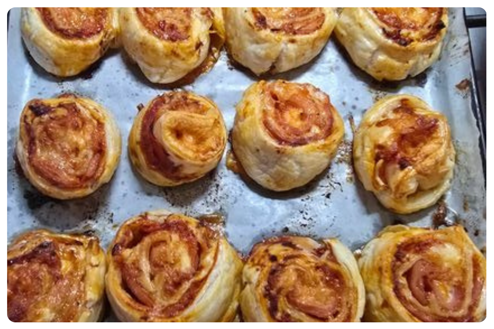 Baked pepperoni pizza roll-ups on a baking sheet.