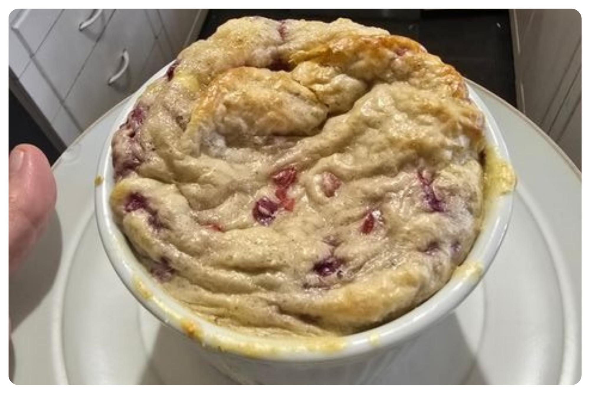 A bowl of unbaked berry cobbler with a thick, lumpy crust and visible red berry filling.