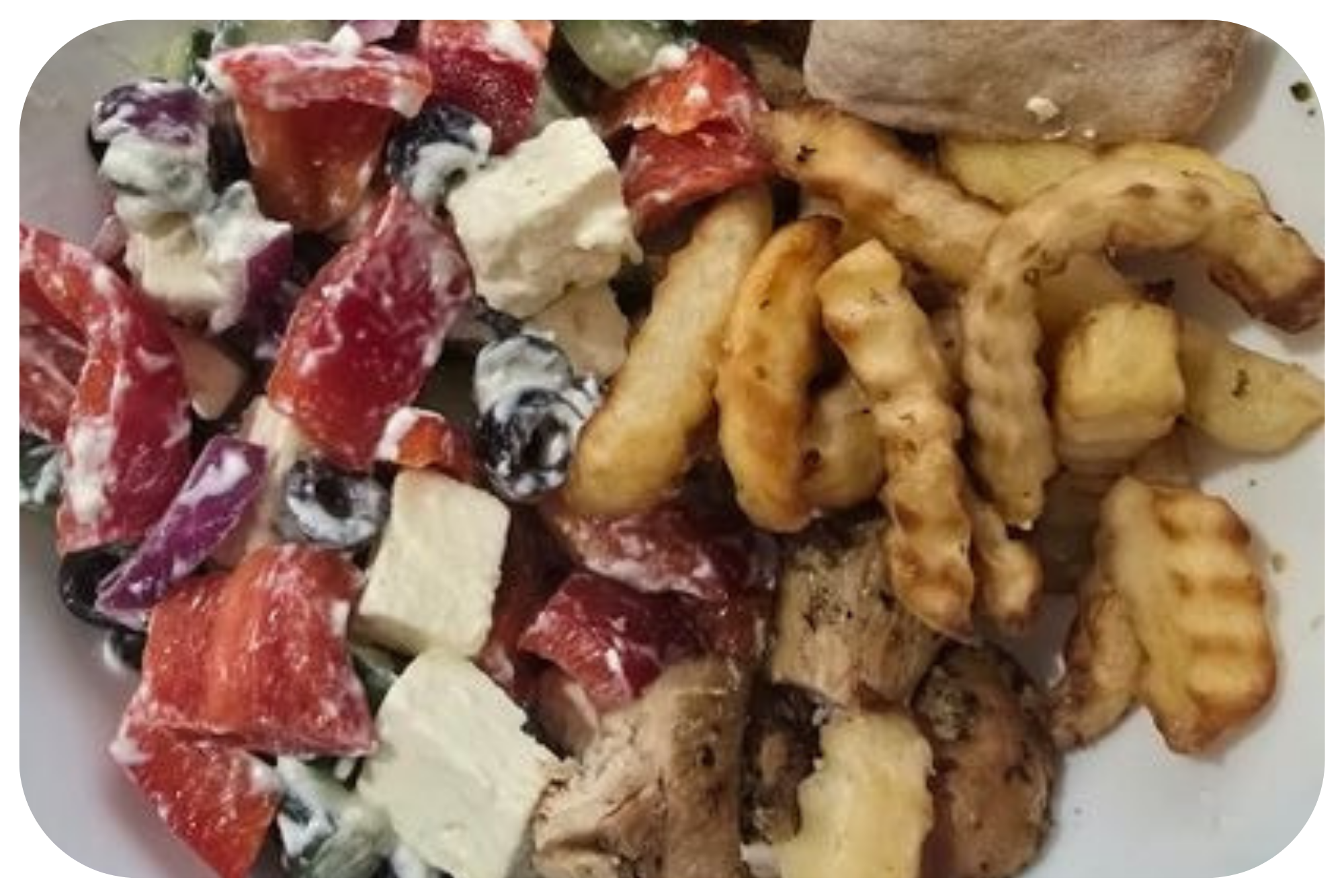 A plate with a colorful fruit salad and a variety of fried foods, including French fries and battered chicken pieces.