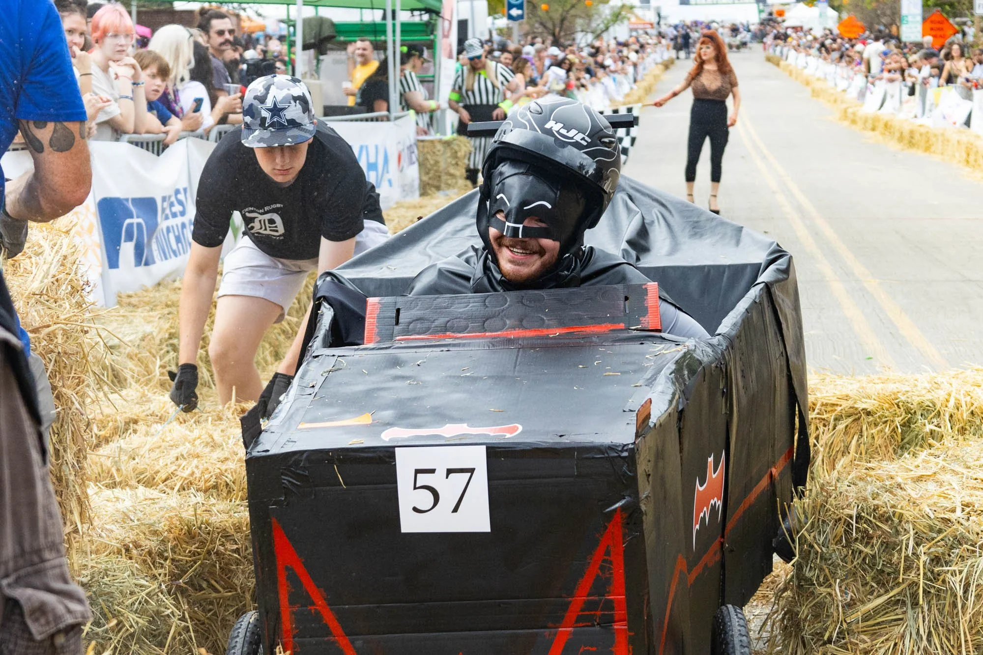 Gilley smiles at the cheering crowd as the Coffin Crew volunteers move hay bales out of his way. 