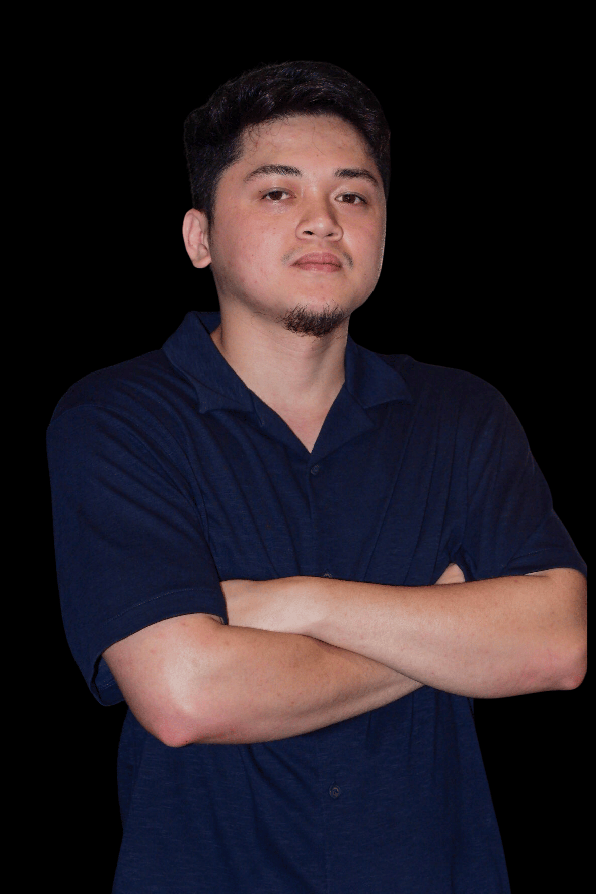 Allon Arroyo - Young man with crossed arms, short dark hair, light facial hair, wearing a navy blue shirt, looking serious, against a black background.