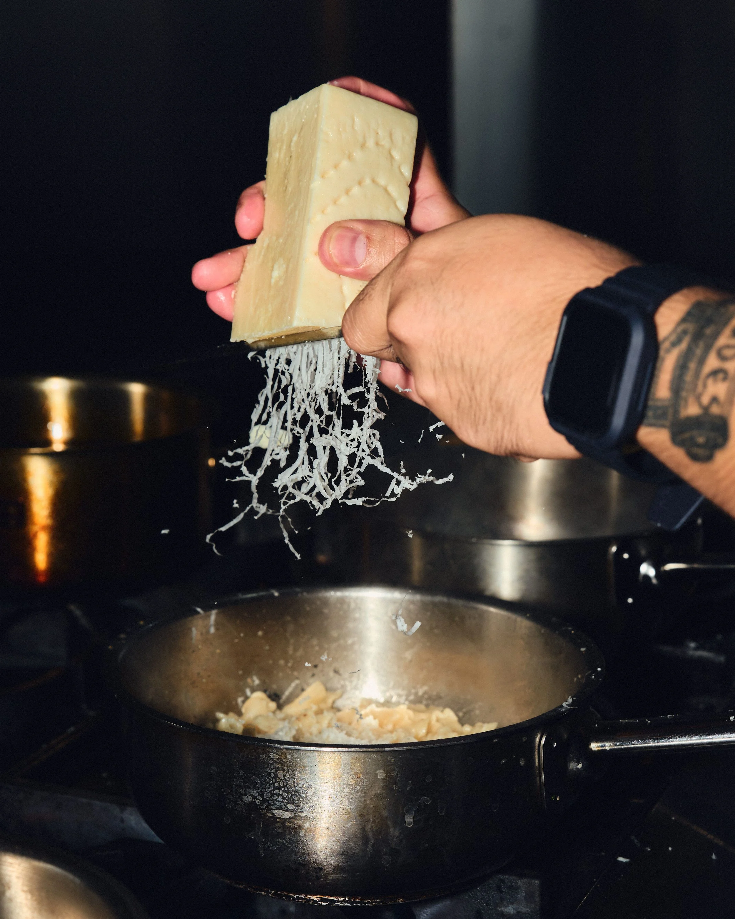 A hand grating a block of cheese