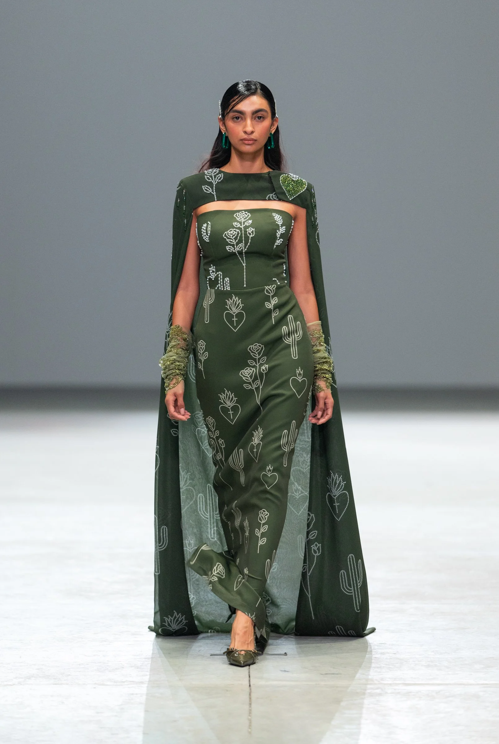  Model in an elegant floor-length green dress with a flowing cape by Vero Solis, seen at Volvo Fashion Week Mexico 2025. A powerful symbol of grace and authenticity. 