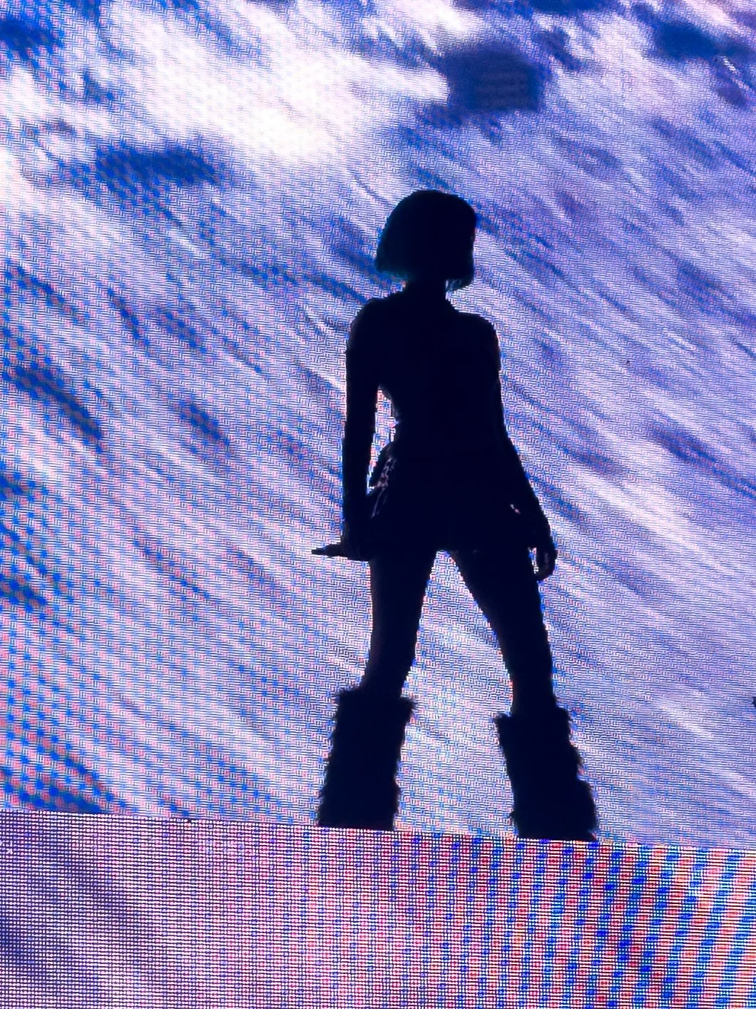 Silhouette of a girl with short hair standing in front of a bright, textured blue background.