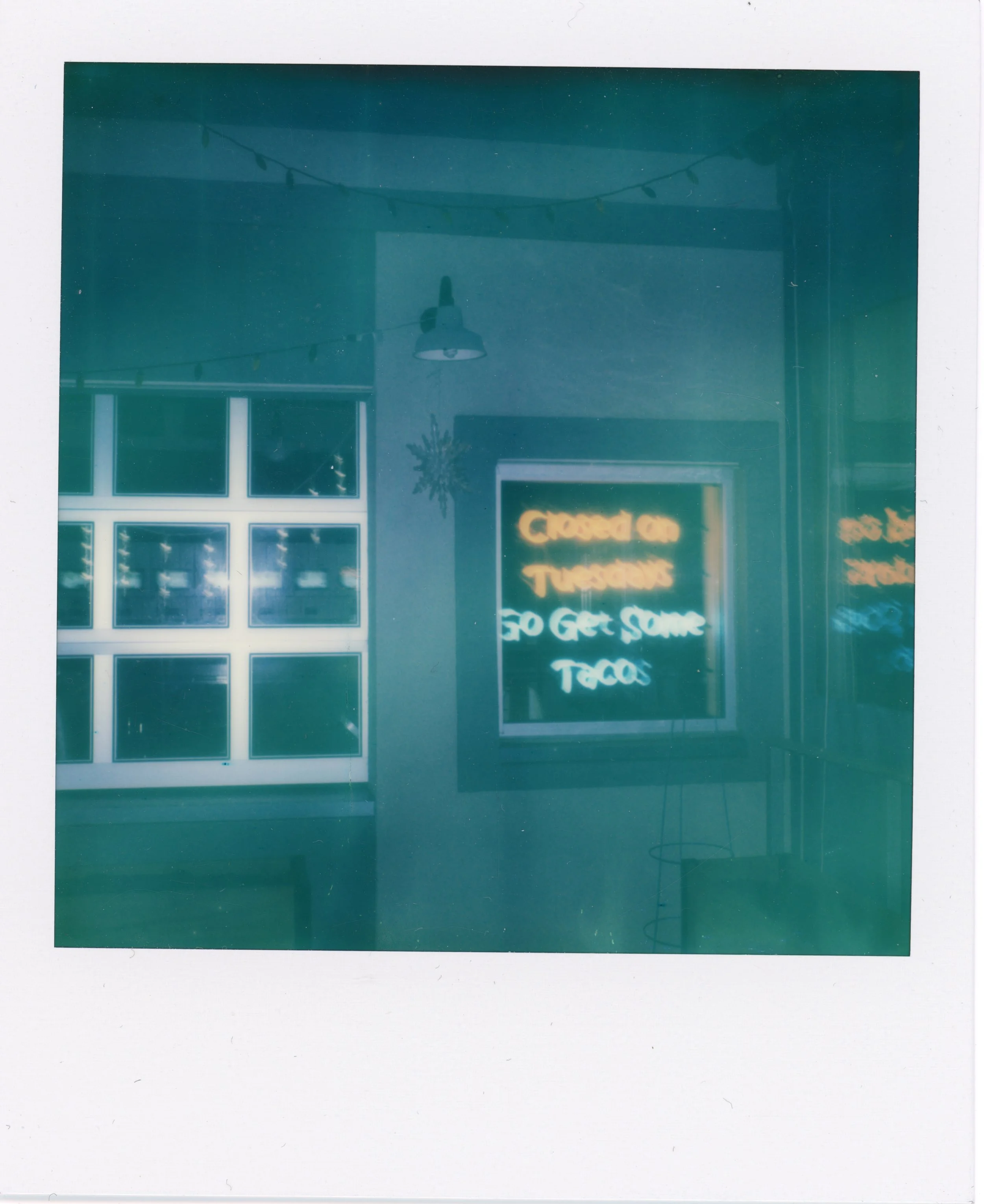 Neon sign in a window reads 'Closed on Tuesdays, to get some tacos.'
