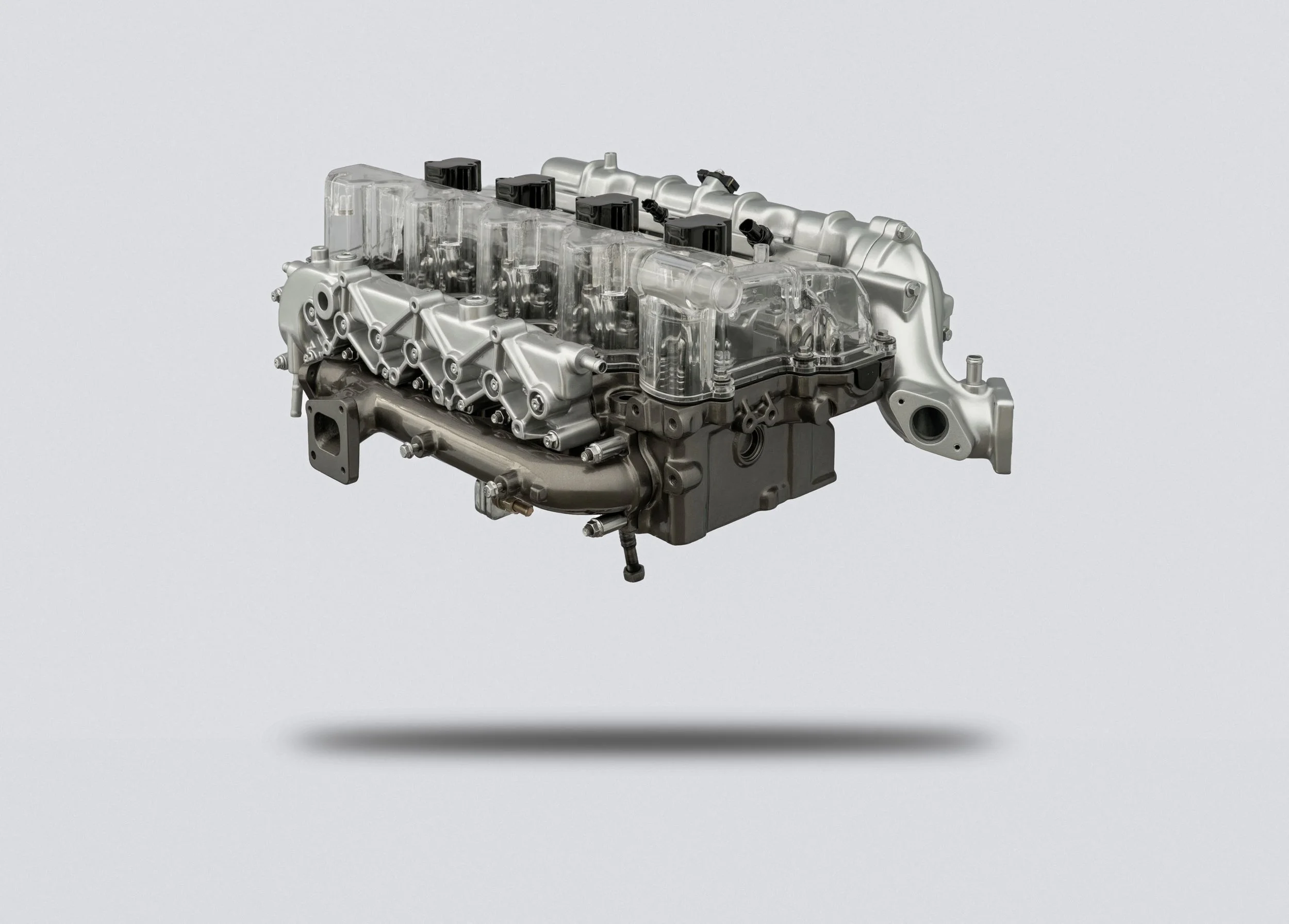 Automobile engine with metallic and plastic parts, floating above a white surface with shadow.