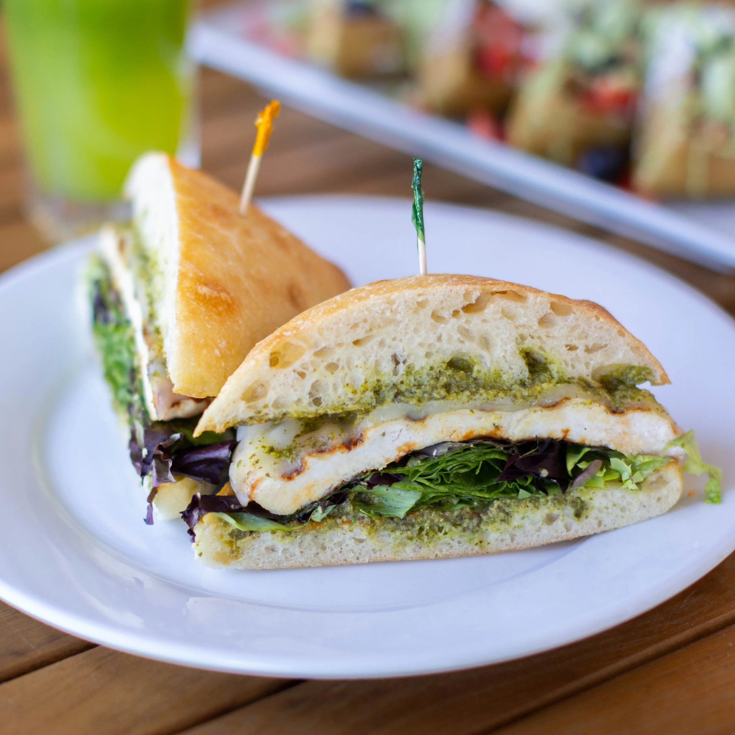 Sandwich with green sauce, lettuce, and cheese on a white plate