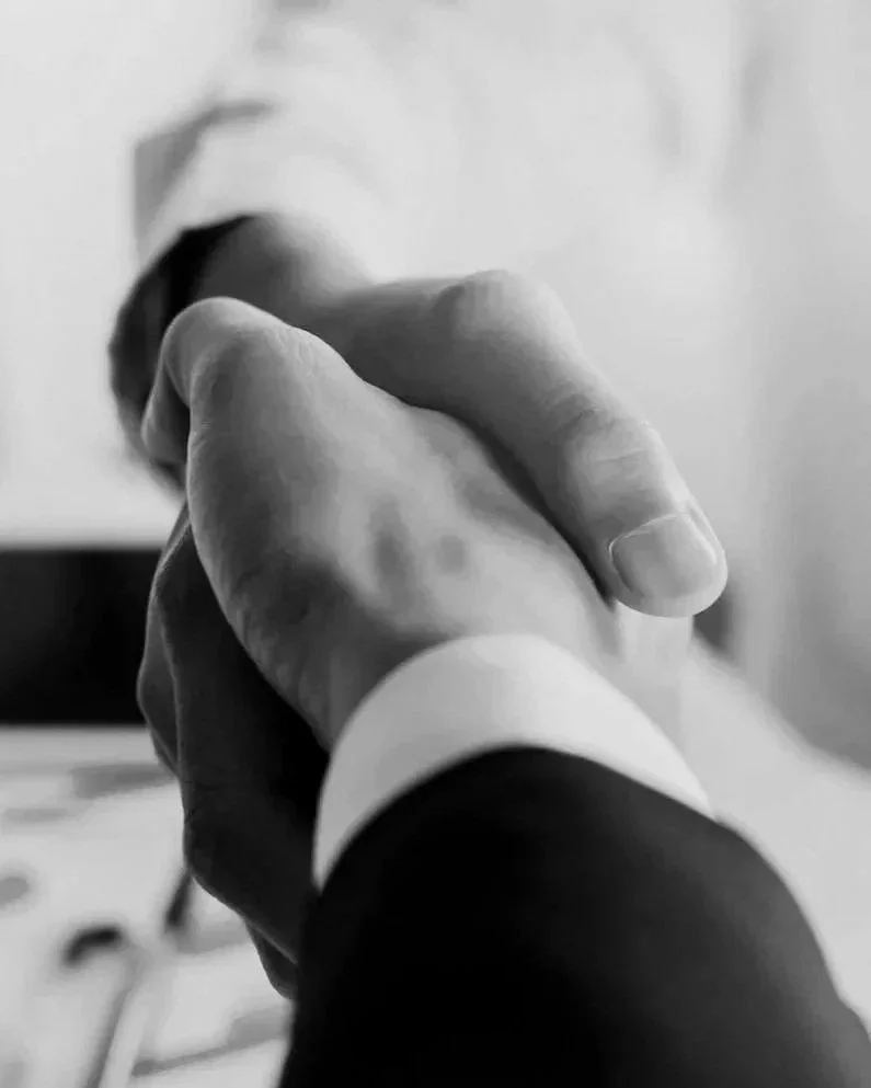 Close-up of two people shaking hands, black and white photo.